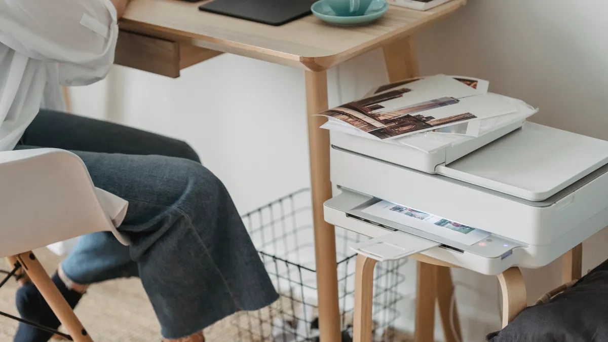 Small home printer beside a laptop on a table