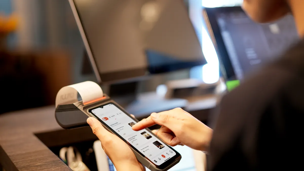 Person using a smartphone beside a receipt printer