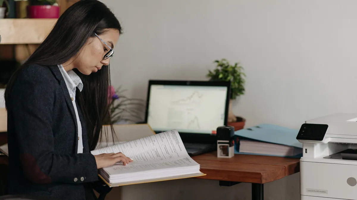 Printer troubleshooting and error recovery — The Complete Guide woman reviewing papers next to a printer